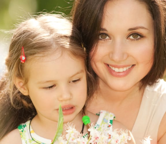 Mother and daughter sitting in a park holding flowers